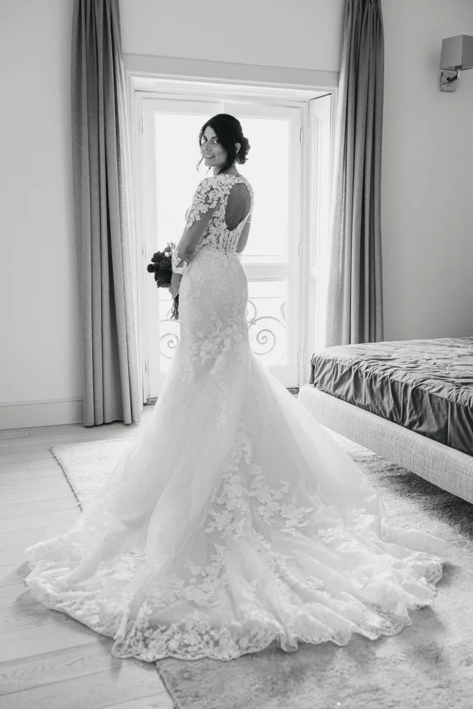 Bride standing in front of the mirror in her lace wedding gown