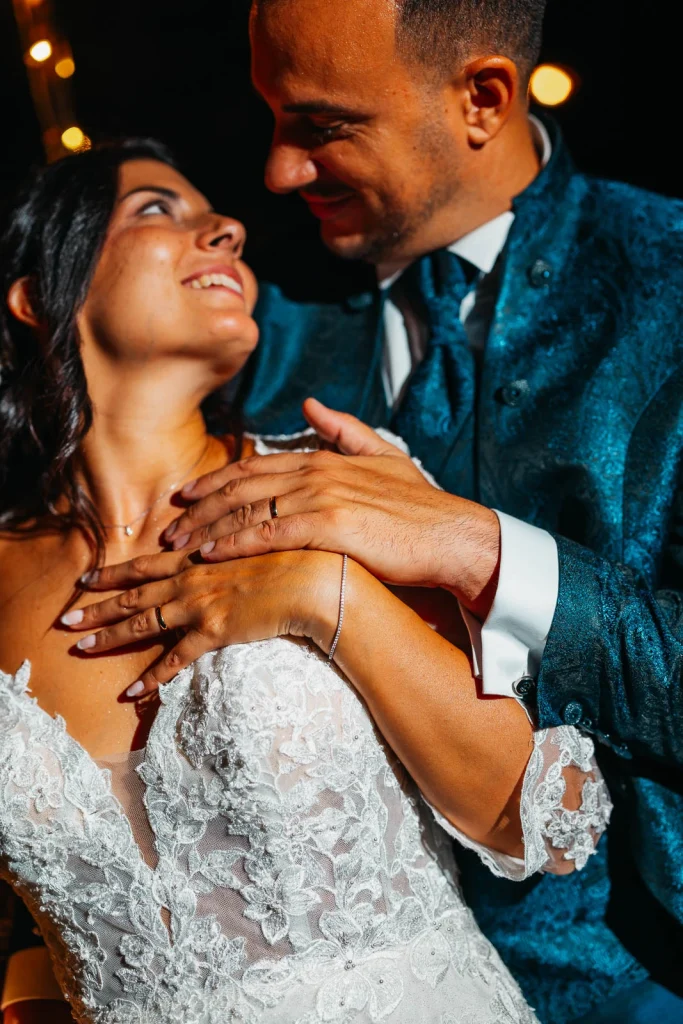 Close-up of bride's hands on groom’s chest, showcasing wedding rings