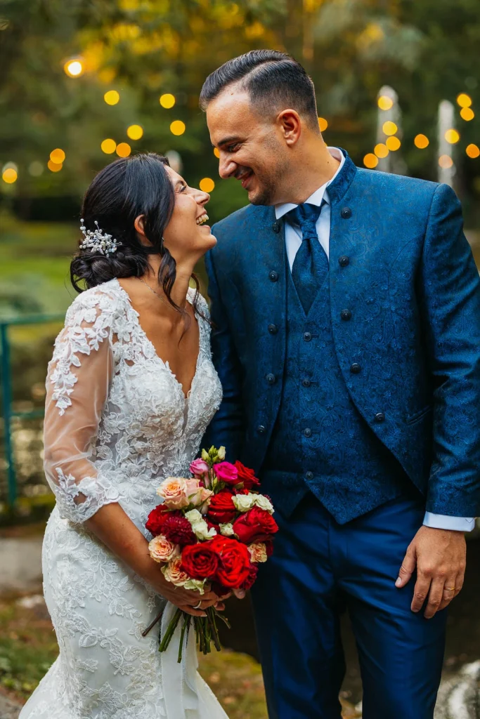 Close-up of bride and groom smiling with bouquet in hand