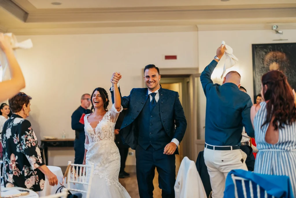 Groom raising his arms celebrating at the dinner reception