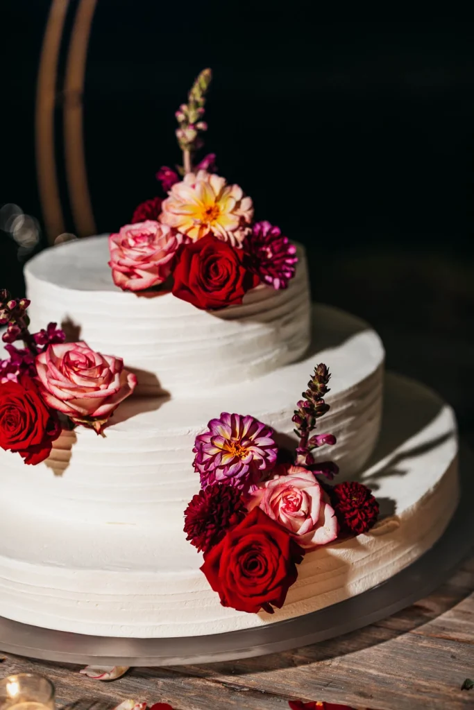 Three-tier wedding cake with red roses and gold touches
