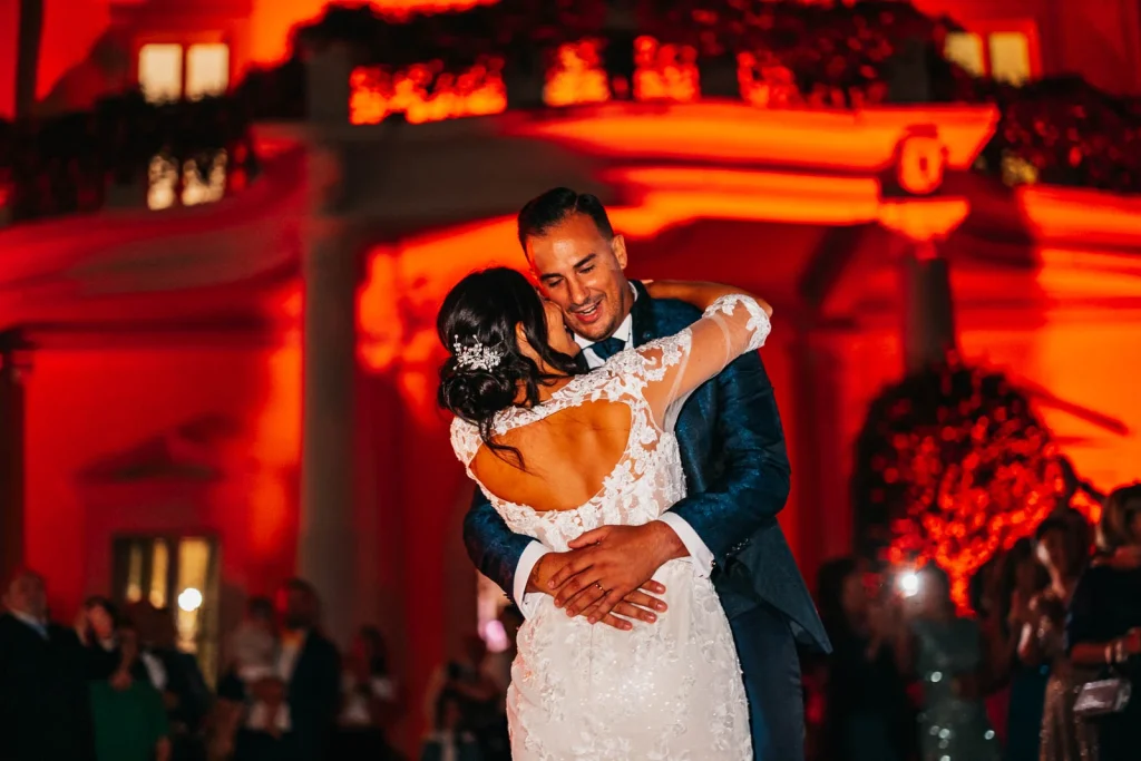 Groom hugging bride during first dance in red light