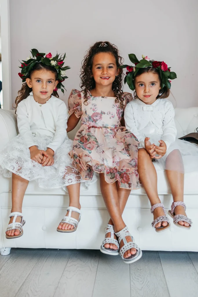 Three flower girls sitting together in matching floral dresses