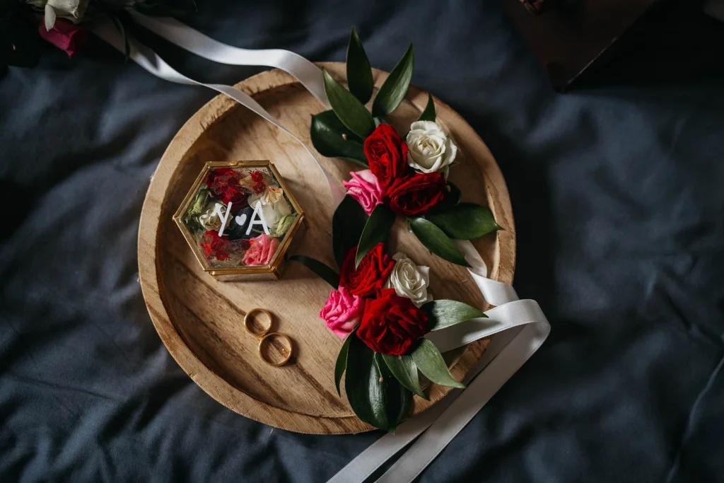 Wedding rings displayed on rustic wood with red roses