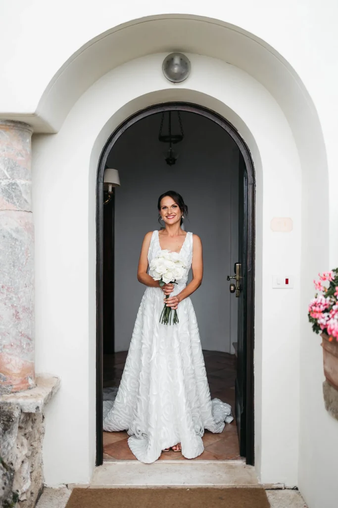 Ravello Wedding at Belmond Hotel Caruso – Amalfi Coast Destination Wedding 29 Bride smiling while standing at the arched entrance of Belmond Hotel Caruso