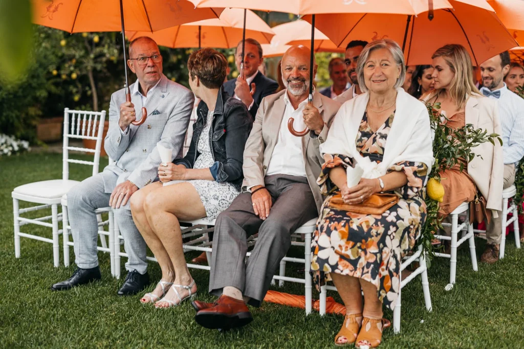 Ravello Wedding at Belmond Hotel Caruso – Amalfi Coast Destination Wedding 33 Guests sitting with umbrellas during rainy outdoor ceremony