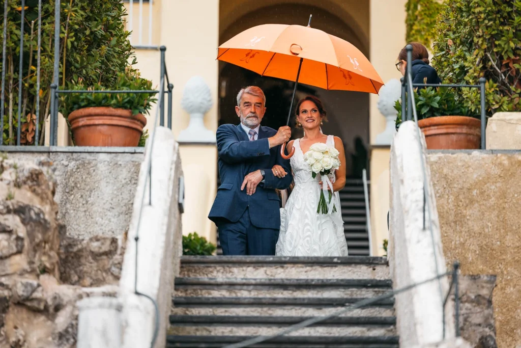 Ravello Wedding at Belmond Hotel Caruso – Amalfi Coast Destination Wedding 36 Bride walking downstairs under orange umbrella with her father