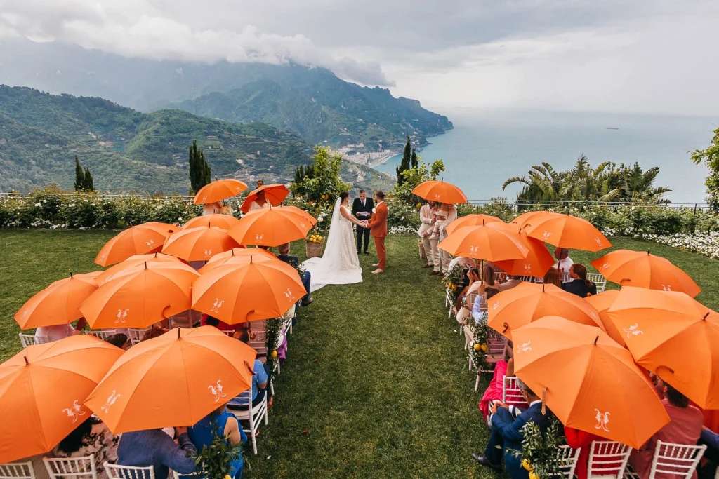 Ravello Wedding at Belmond Hotel Caruso – Amalfi Coast Destination Wedding 40 Guests seated with umbrellas during the outdoor ceremony in Ravello