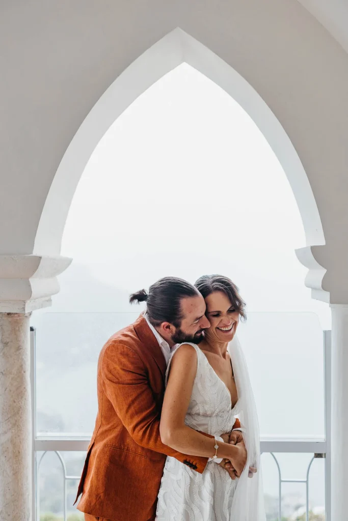 Ravello Wedding at Belmond Hotel Caruso – Amalfi Coast Destination Wedding 51 Groom hugging the bride from behind while overlooking the Amalfi Coast