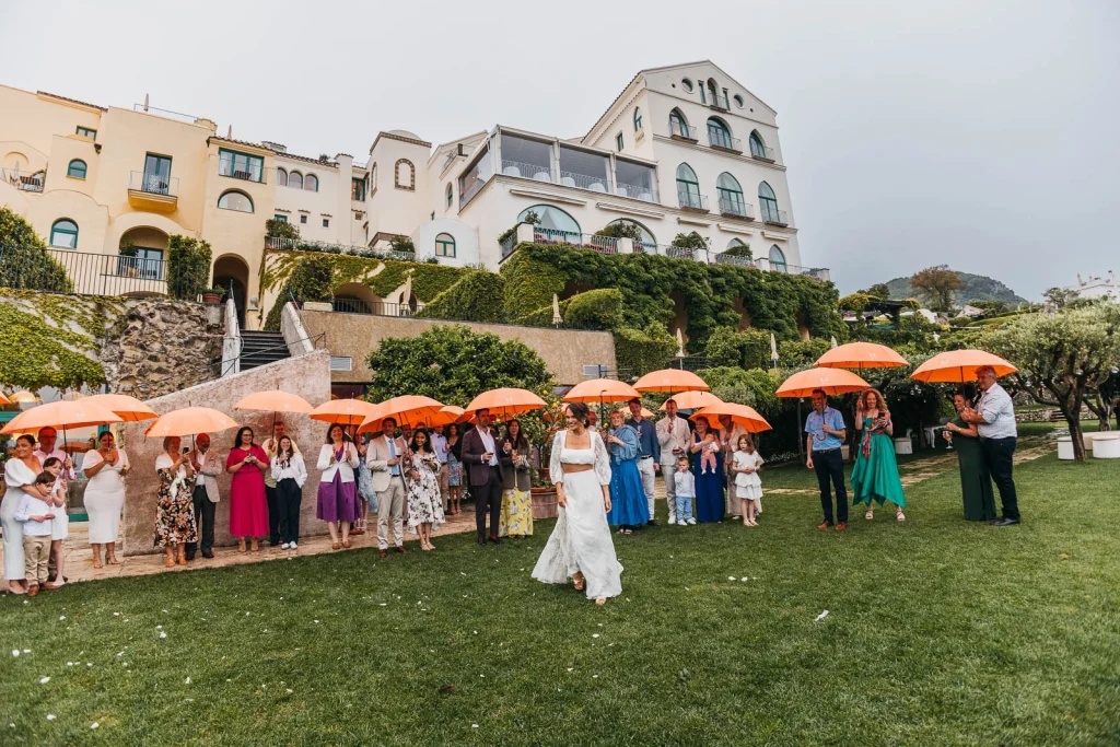 Ravello Wedding at Belmond Hotel Caruso – Amalfi Coast Destination Wedding 55 Group photo of guests with orange umbrellas on the lawn