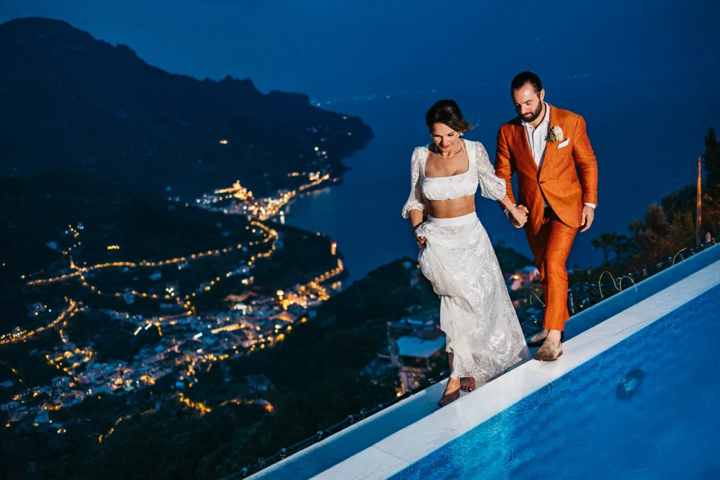 Ravello Wedding at Belmond Hotel Caruso – Amalfi Coast Destination Wedding 77 Bride and groom standing on a ledge with Amalfi Coast below