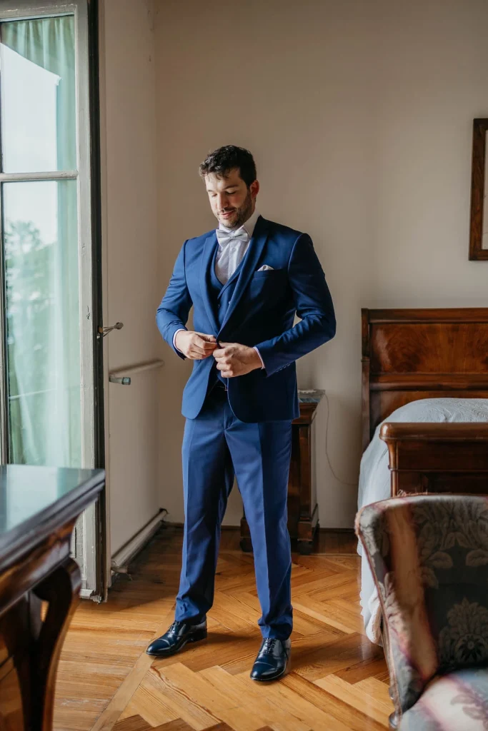 Dream Wedding at Villa Le Due Torrette in Erba: The Elegance of a Lake Como Celebration 15 Groom posing in a blue suit inside the room at Villa Le Due Torrette