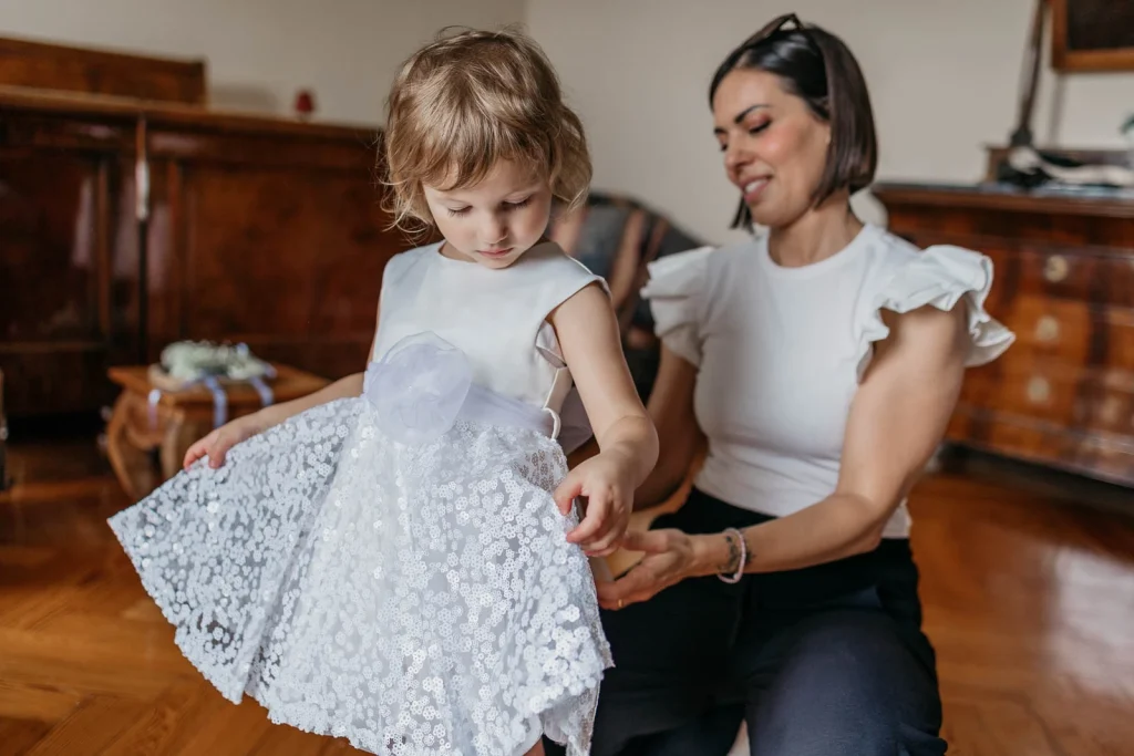 Dream Wedding at Villa Le Due Torrette in Erba: The Elegance of a Lake Como Celebration 16 Little girl trying on a dress before the wedding ceremony