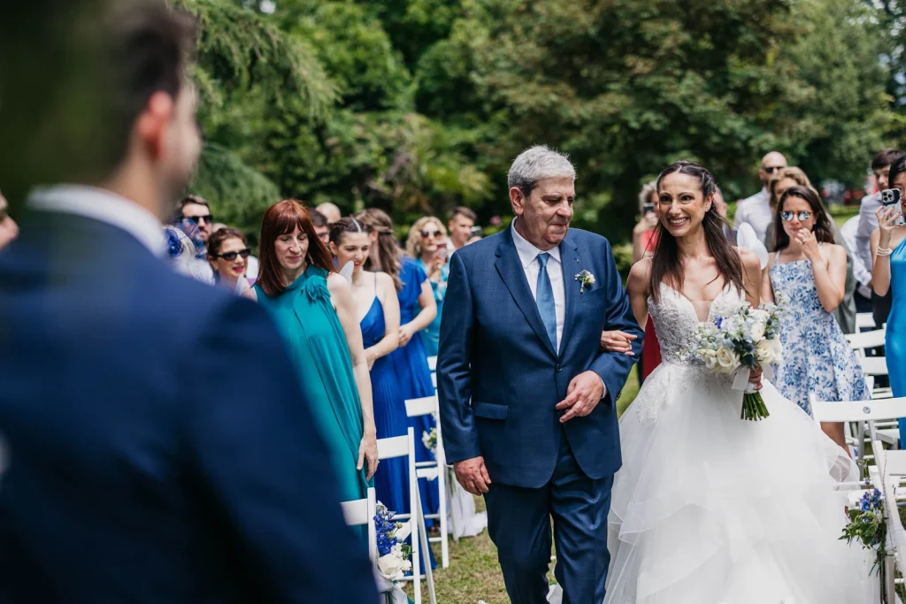 Dream Wedding at Villa Le Due Torrette in Erba: The Elegance of a Lake Como Celebration 35 Bride walking down the aisle with her father at Villa Le Due Torrette
