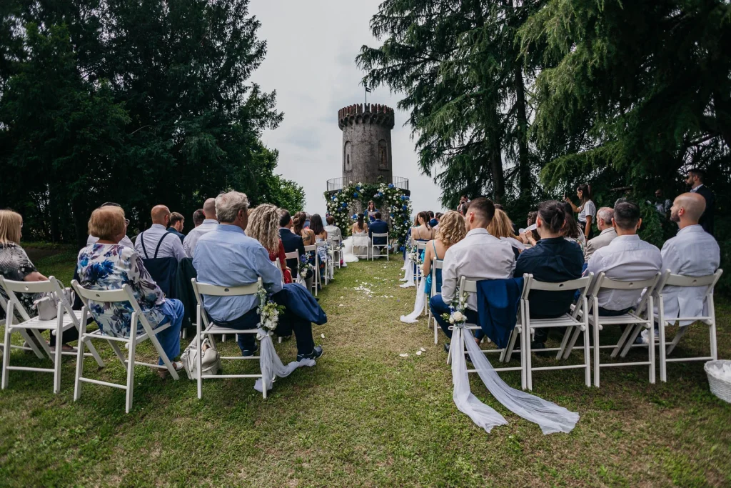 Dream Wedding at Villa Le Due Torrette in Erba: The Elegance of a Lake Como Celebration 36 Wedding ceremony guests seated in front of the iconic tower at Villa Le Due Torrette
