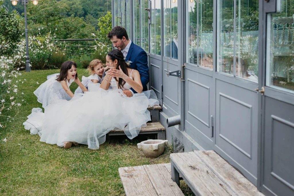 Dream Wedding at Villa Le Due Torrette in Erba: The Elegance of a Lake Como Celebration 74 Groom joins bride and children seated outside at Villa Le Due Torrette