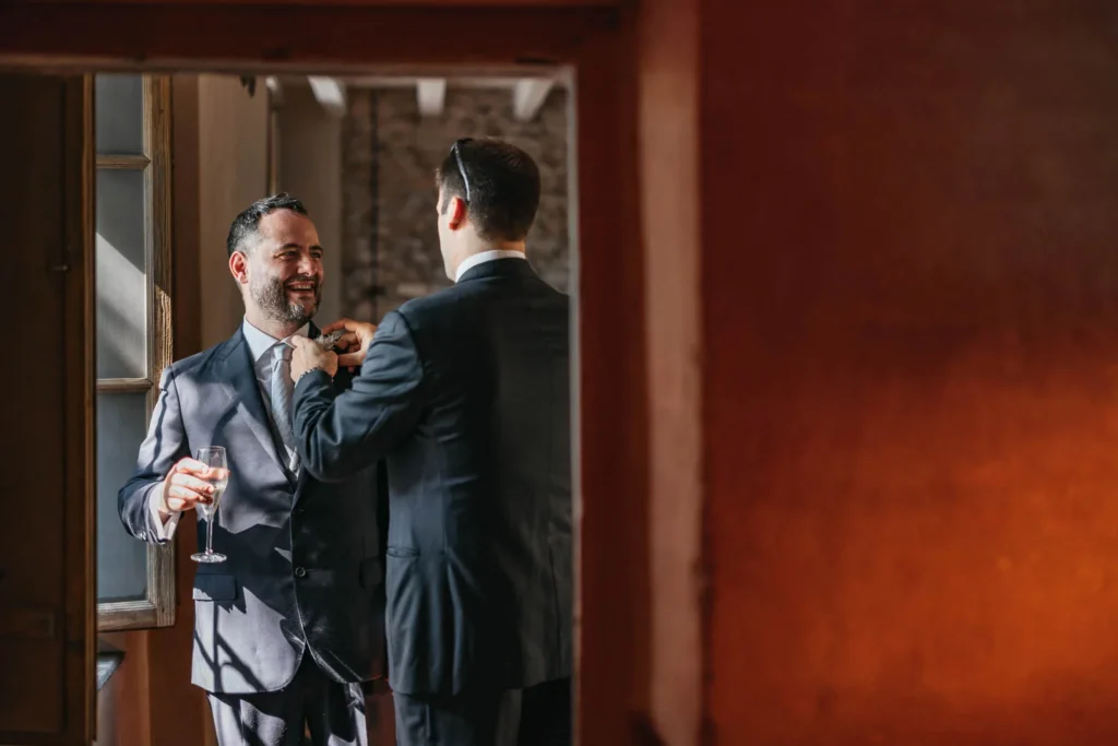 Groom smiling while buttoning jacket at Convento dell’Annunciata
