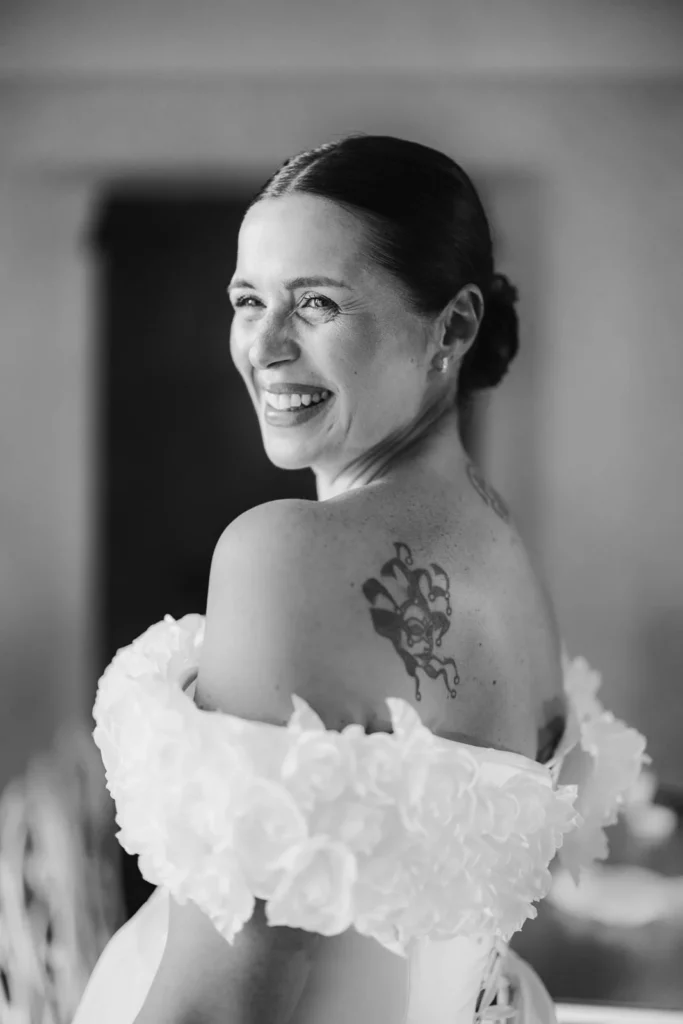Bride in off-shoulder wedding gown standing between columns of the cloister