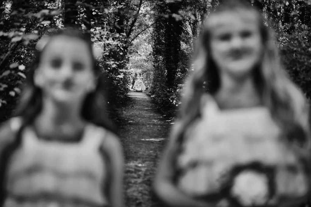 Soft-focus black and white photo of flower girls walking in the forest