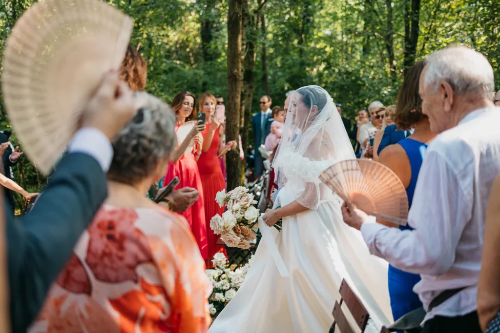 Bride smiling and holding bouquet while walking through the woods