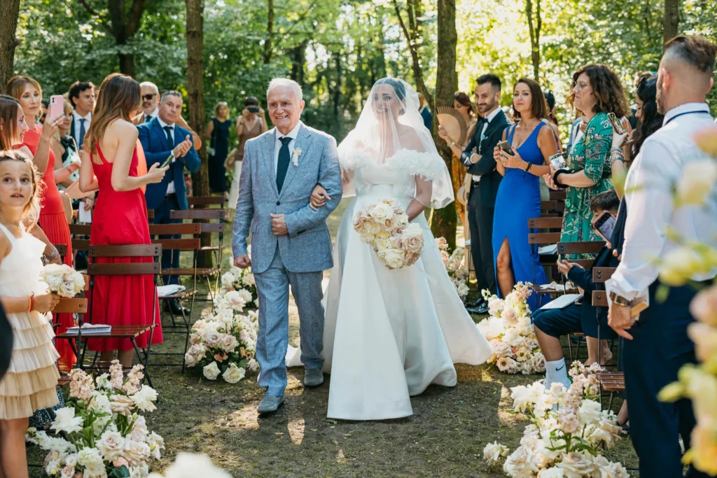 Bride walking down the aisle with her father through the forest of Convento dell’Annunciata