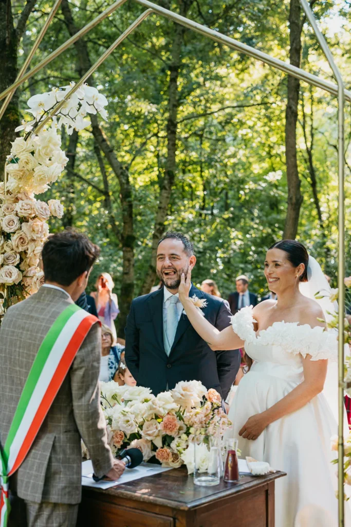 Bride and groom smiling with the celebrant in the natural woodland setting