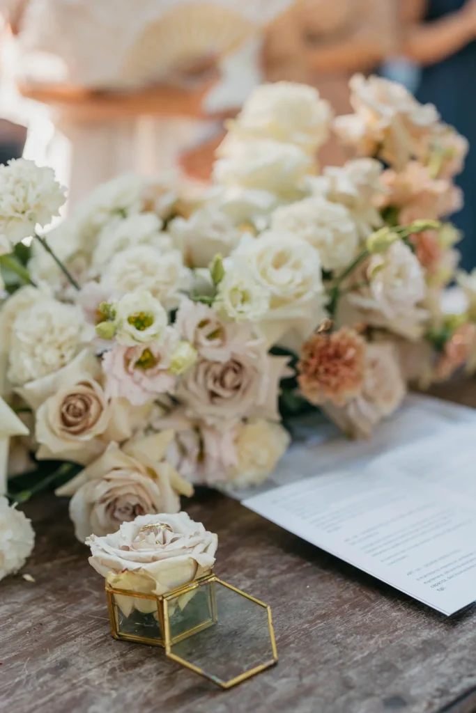 Close-up of pastel rose bouquet and ceremony book on wooden table