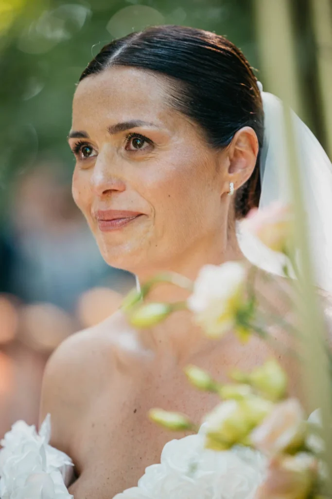 Bride with serene expression surrounded by greenery and soft light