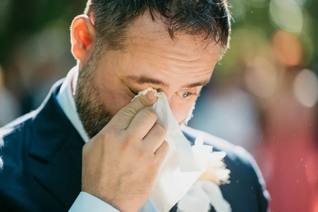 Groom wiping away tears during emotional forest ceremony