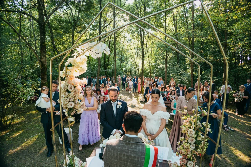 Panoramic view of the ceremony in the forest with floral arch and guests