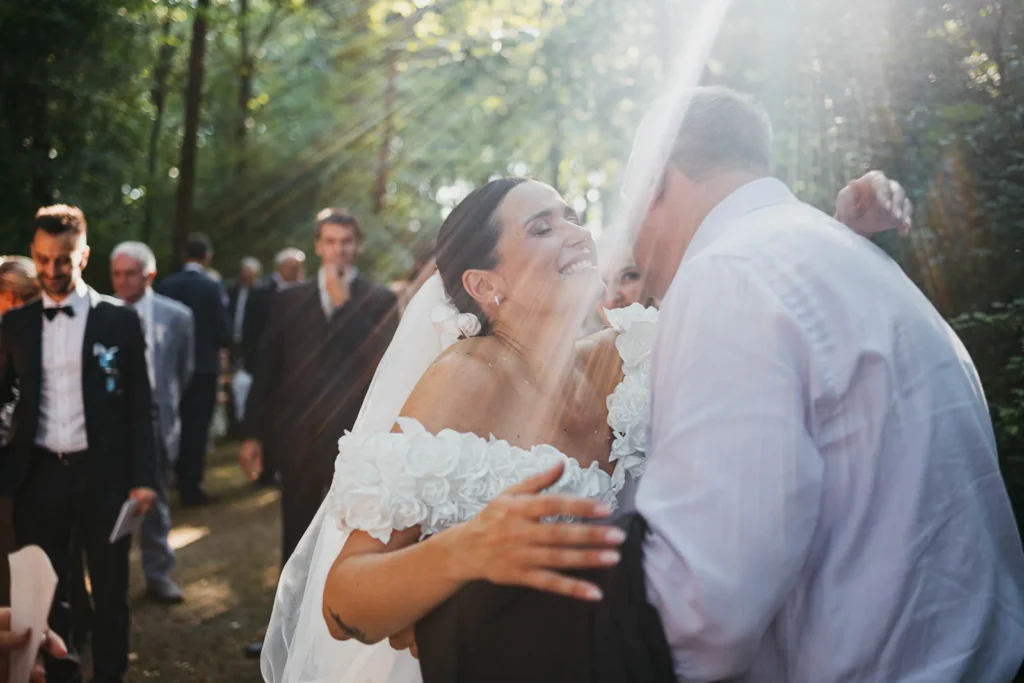 Bride laughing and hugging guests after the ceremony in the woods