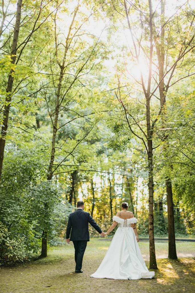 Couple walking hand in hand down the green forest aisle of Convento dell’Annunciata