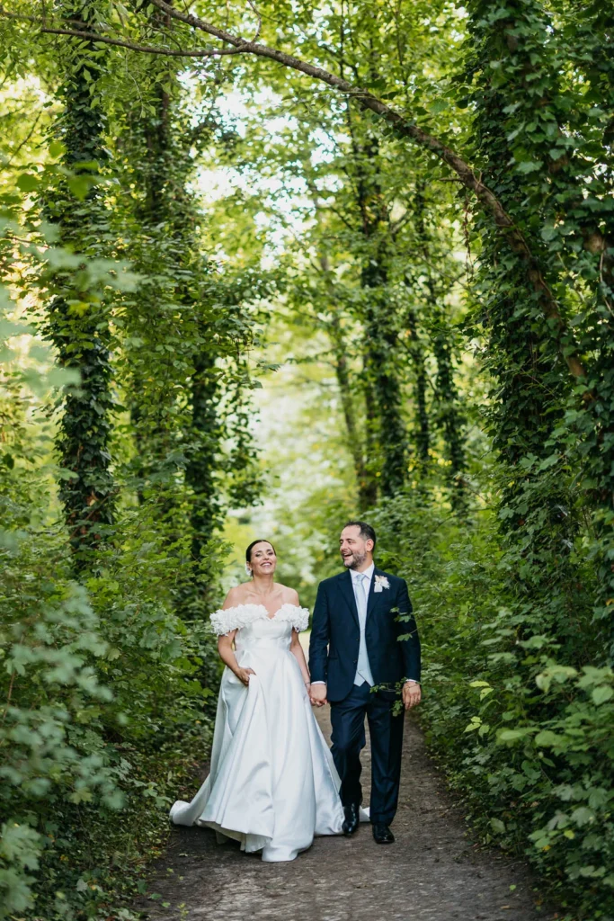 Bride and groom exiting the woods toward the cloister for the aperitif