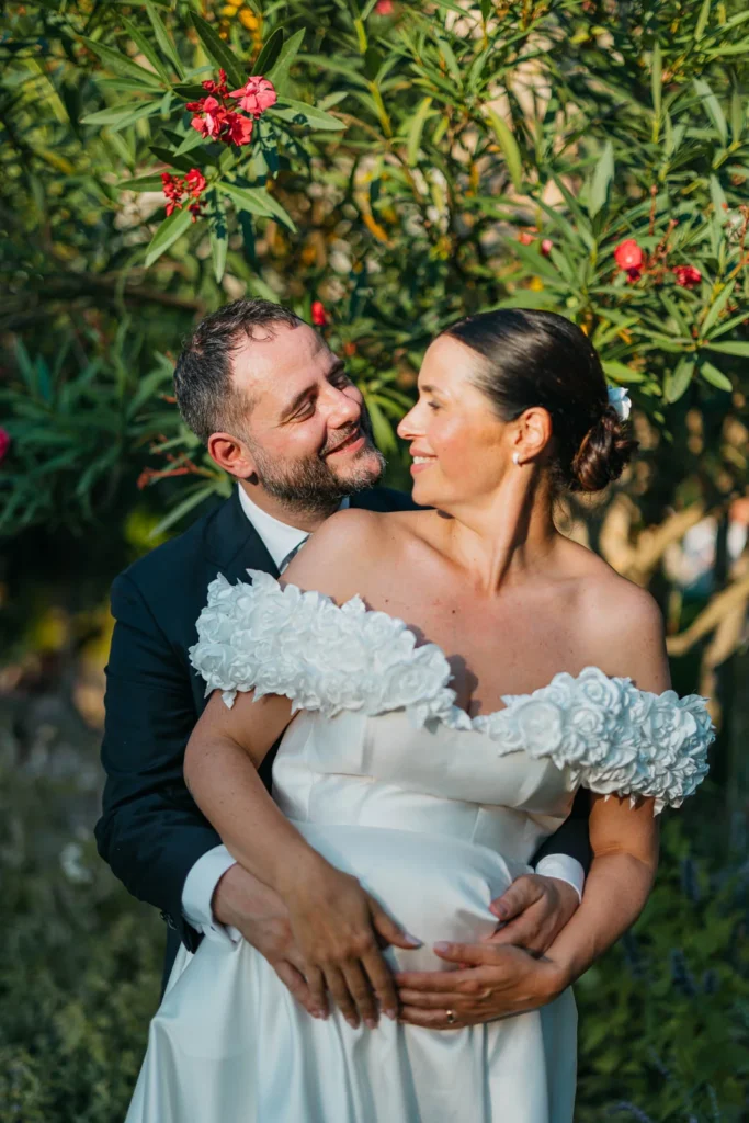 Groom embracing the bride while holding their child during golden hour