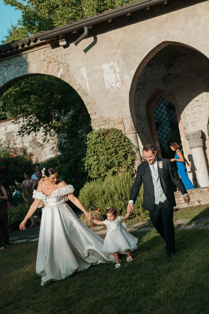 Bride walking with her husband and baby through the ancient cloister arches