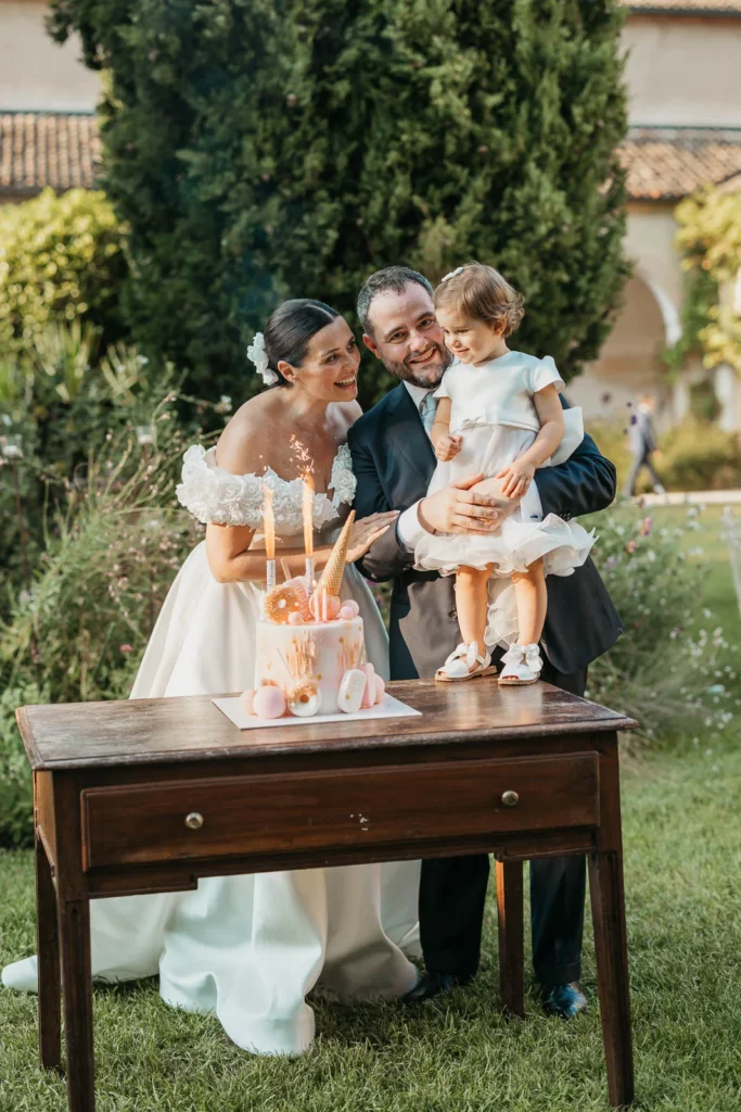 Bride and groom with their children sitting on a vintage wooden table outdoors