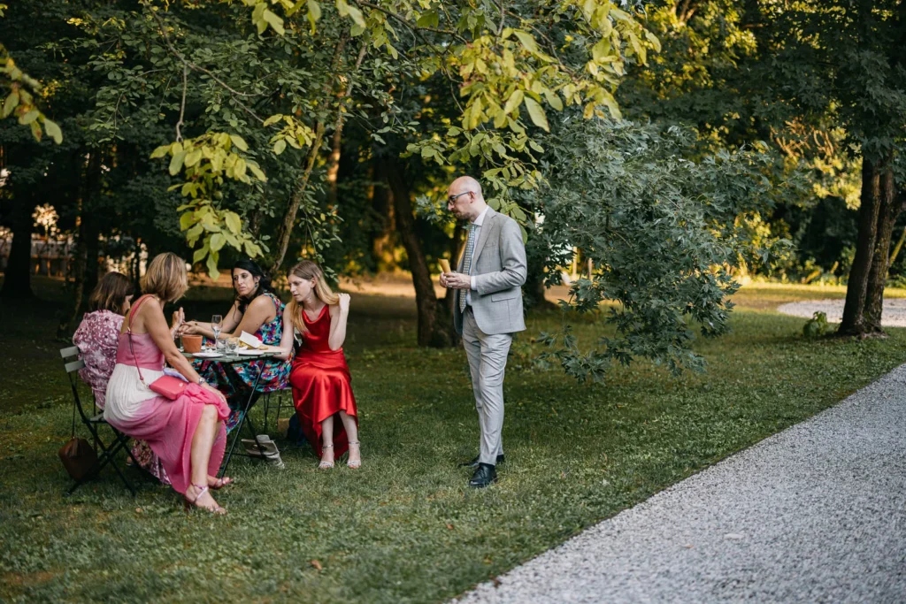 Guests chatting and relaxing under the trees during aperitif hour