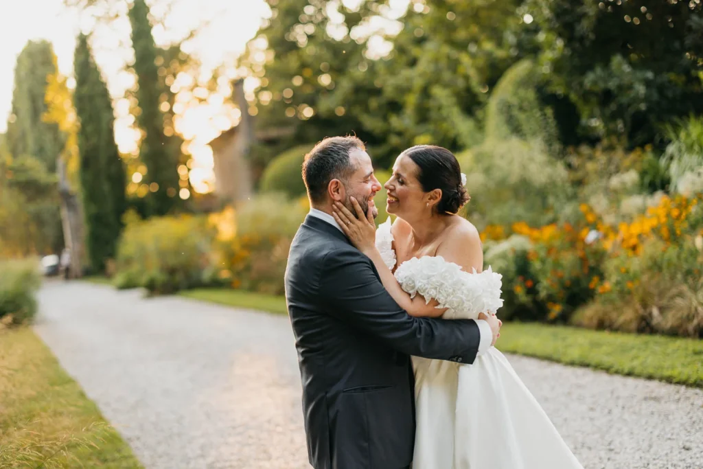 Groom and bride holding each other in the soft light of early evening
