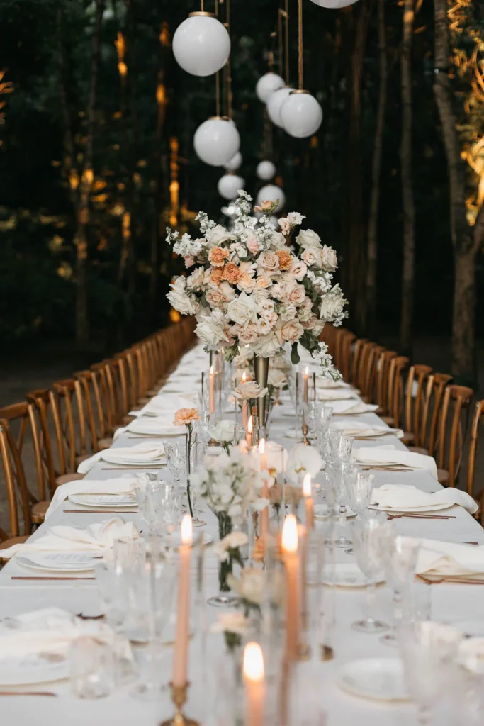 Bride and groom at the head of the table during candlelit forest dinner