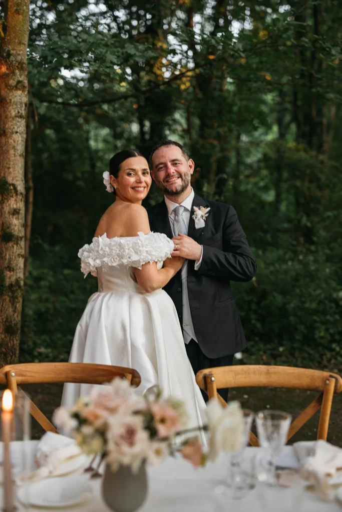 Bride and groom smiling at the reception table in the forest of Convento dell’Annunciata