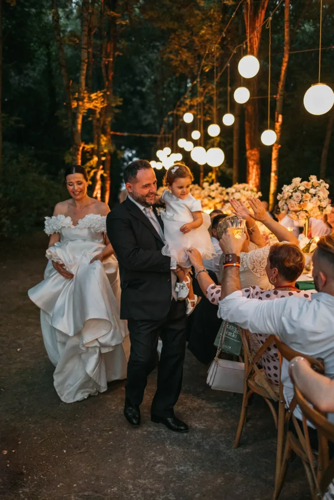 Bride laughing with guests during outdoor speeches under fairy lights