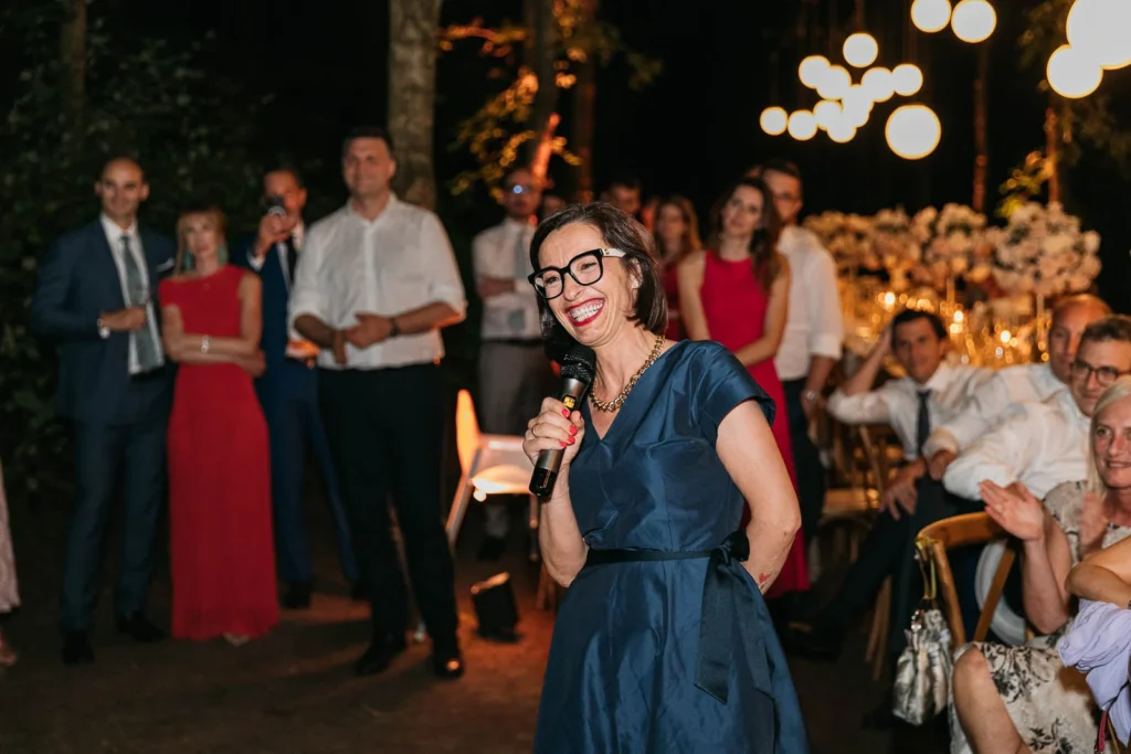 A wedding guest giving a speech with a smile and microphone in hand