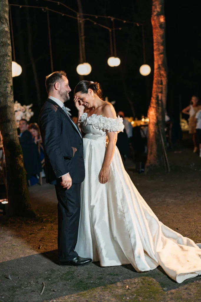 Bride and groom’s romantic dance under string lights among trees