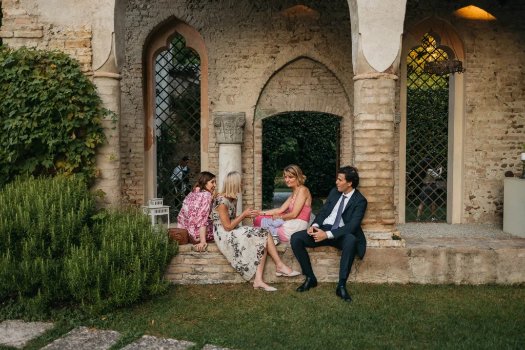 Wedding guests seated by stone arches of the convent during cocktail hour